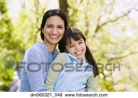 Stock Photo - Hispanic mother and daughter smiling outdoors. Fotosearch