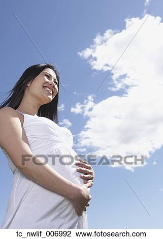 Low angle view of pregnant Asian woman under blue sky View Large Photo Image Stock Image - Low angle view of pregnant Asian woman under blue sky. Fotosearch