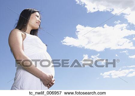 Low angle view of pregnant Asian woman under blue sky View Large Photo Image Stock Photo - Low angle view of pregnant Asian woman under blue sky. Fotosearch