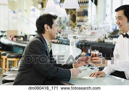 Male bartender serving man drink at bar View Large Photo Image Stock Image - Male bartender serving man drink at bar. Fotosearch