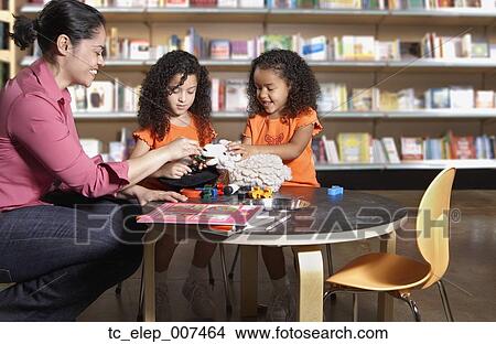 Picture - Mother with two young daughters in library. Fotosearch
