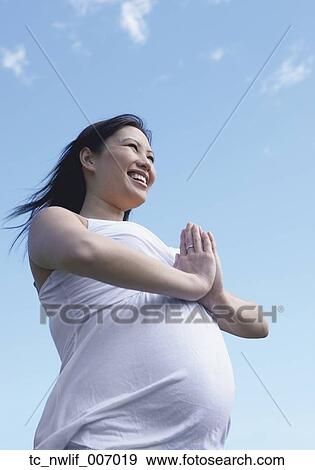 Pregnant Asian woman doing yoga outdoors View Large Photo Image Stock Photo - Pregnant Asian woman doing yoga outdoors. Fotosearch