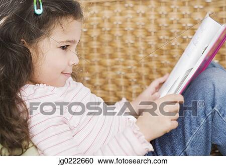 Stock Image - Profile of young Hispanic girl reading book. Fotosearch