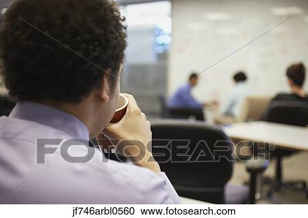 Stock Image - Rear view of businessman drinking coffee. Fotosearch