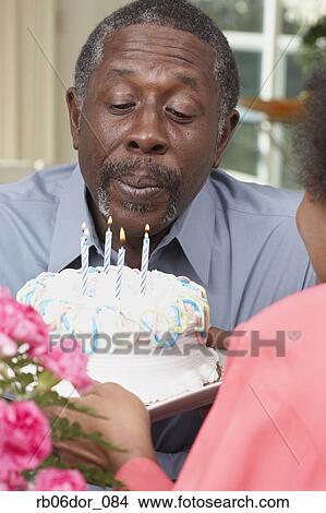 Senior African American man blowing out birthday candles View Large Photo Image Picture - Senior African American man blowing out birthday candles. Fotosearch