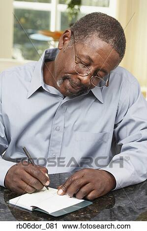 Stock Image - Senior African American man writing check. Fotosearch