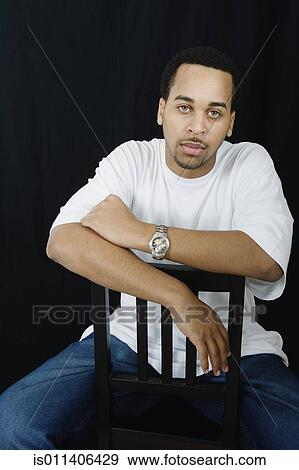 Studio shot of African American man sitting in chair View Large Photo Image Stock Photo - Studio shot of African American man sitting in chair. Fotosearch