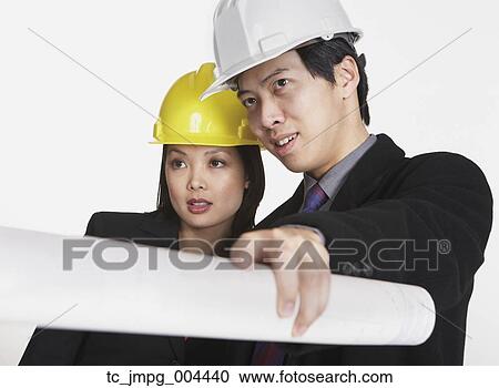Stock Image - Studio shot of Asian businesspeople wearing hard hats. Fotosearch