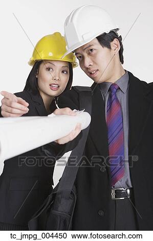 Stock Image - Studio shot of Asian businesspeople wearing hard hats. Fotosearch