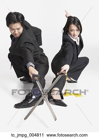 Stock Image - Studio shot of Asian businesspeople with crossed swords. Fotosearch