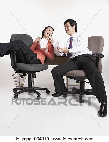 Stock Photo - Studio shot of Asian businesspeople eating take out. Fotosearch