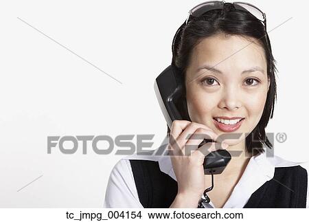 Picture - Studio shot of Asian businesswoman talking on telephone. Fotosearch