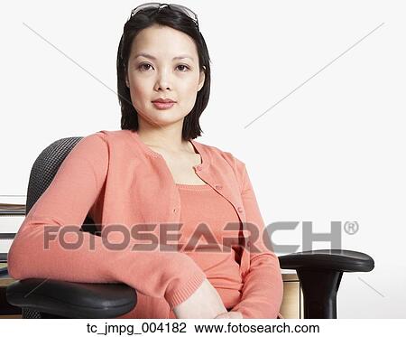 Stock Image - Studio shot of Asian businesswoman sitting in chair. Fotosearch