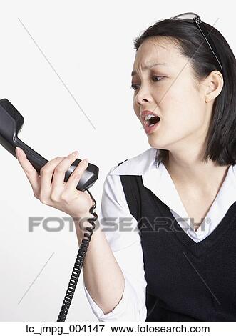 Stock Photo - Studio shot of Asian businesswoman yelling at telephone. Fotosearch