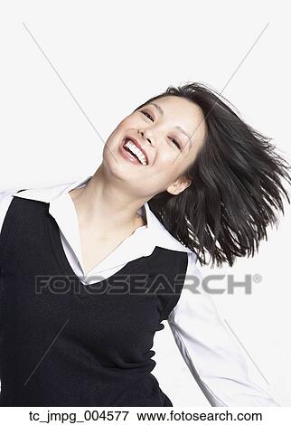 Stock Photo - Studio shot of Asian woman tossing hair and smiling. Fotosearch