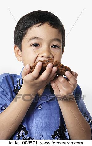 Stock Image - Studio shot of young boy eating cookie. Fotosearch