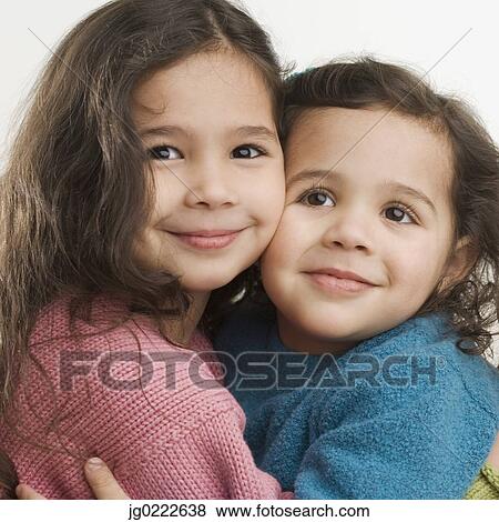 Stock Photo - Studio shot of young Hispanic sisters hugging. Fotosearch