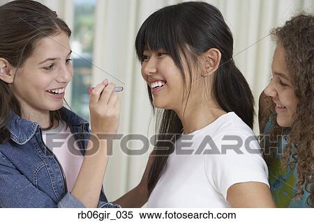Stock Photography - Teenaged girls applying lipstick. Fotosearch