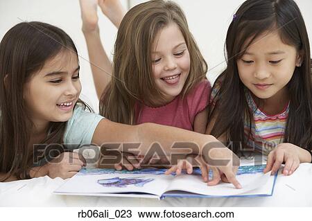 Stock Image - Three young girls reading book. Fotosearch