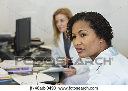 Two businesswomen at desks View Large Photo Image Stock Image - Two businesswomen at desks. Fotosearch