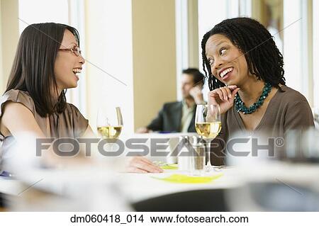 Picture - Two businesswomen laughing in restaurant. Fotosearch