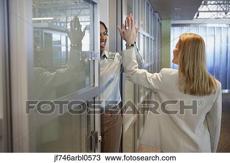 Two female coworkers giving each other a high five View Large Photo Image Stock Image - Two female coworkers giving each other a high five. Fotosearch