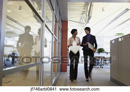Two female coworkers talking in office View Large Photo Image Stock Image - Two female coworkers talking in office. Fotosearch