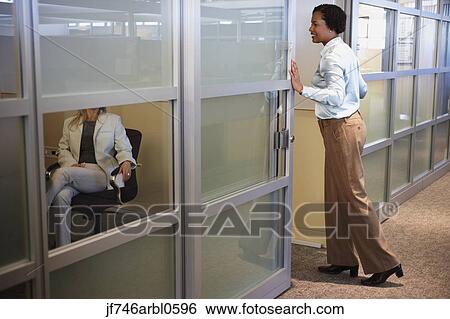 Two female coworkers talking in office View Large Photo Image Stock Photograph - Two female coworkers talking in office. Fotosearch