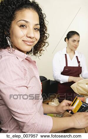Stock Photo - Woman holding credit card at checkout. Fotosearch