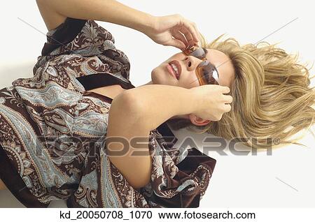 Stock Image - Woman laying on floor wearing sunglasses. Fotosearch