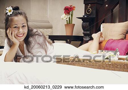 Stock Photo - Woman lying on bed with breakfast tray. Fotosearch