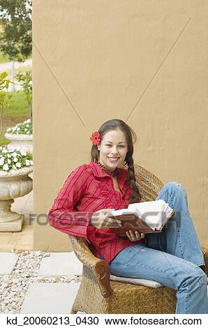 Stock Image - Woman reading book outdoors. Fotosearch