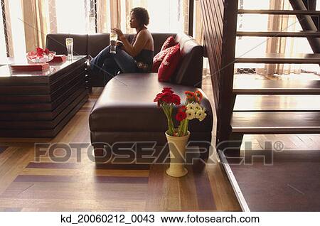 Stock Image - Woman sitting on sofa. Fotosearch
