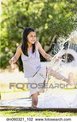 Stock Image - Young Hispanic girl playing in water outdoors. Fotosearch