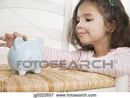 Young Hispanic girl putting coin in piggy bank View Large Photo Image Stock Photo - Young Hispanic girl putting coin in piggy bank. Fotosearch