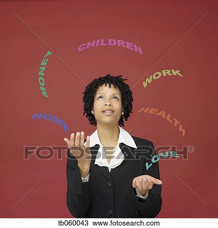 Stock Image - African businesswoman juggling words representing busy life. Fotosearch