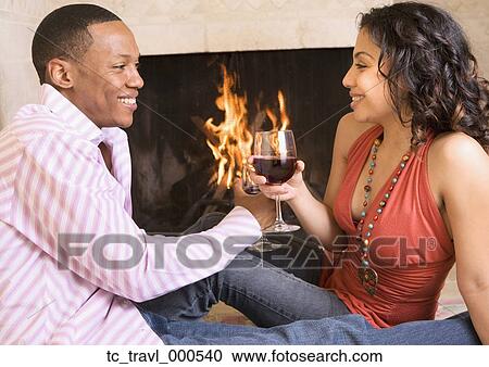Stock Image - African couple toasting next to fireplace. Fotosearch