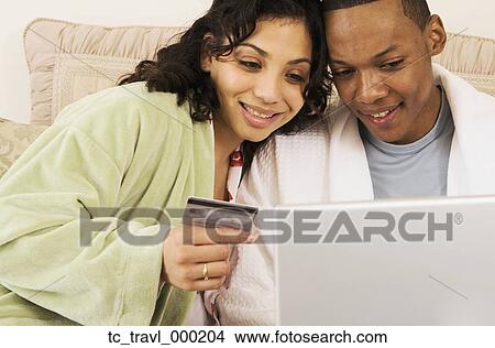 African couple with credit card using laptop in bed View Large Photo Image Picture - African couple with credit card using laptop in bed. Fotosearch