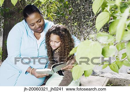 African mother and daughter reading outdoors View Large Photo Image Stock Image - African mother and daughter reading outdoors. Fotosearch