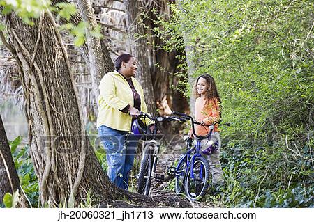 Stock Image - African mother and daughter with bicycles in woods. Fotosearch