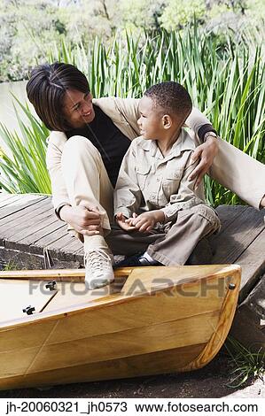 African mother and son sitting on dock next to canoe View Large Photo Image Stock Image - African mother and son sitting on dock next to canoe. Fotosearch