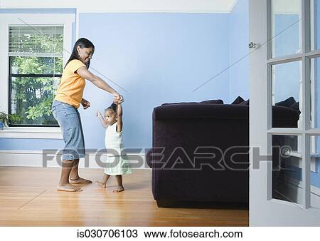 Stock Image - African mother and young daughter dancing in livingroom. Fotosearch