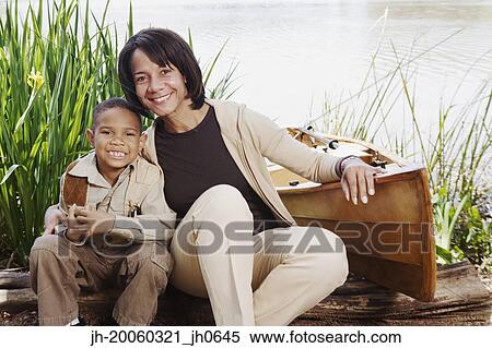 Stock Photography - African mother and young son smiling next to canoe. Fotosearch