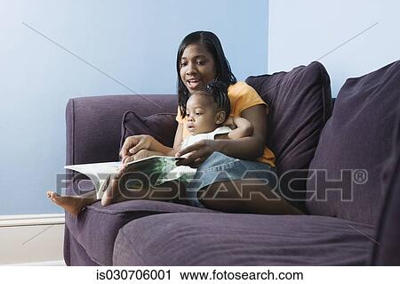 African mother reading to young daughter on sofa View Large Photo Image Stock Image - African mother reading to young daughter on sofa. Fotosearch