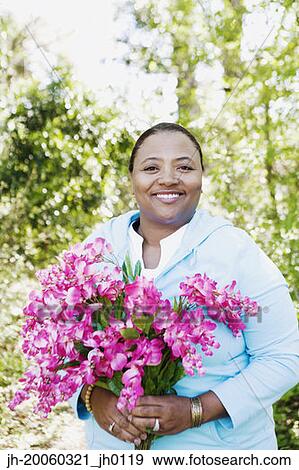 African woman holding bouquet of flowers outdoors View Large Photo Image Stock Photo - African woman holding bouquet of flowers outdoors. Fotosearch