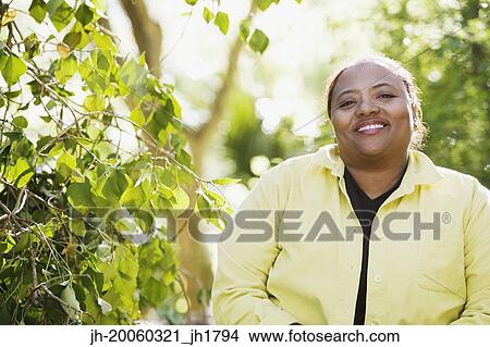 Picture - African woman smiling in woods. Fotosearch
