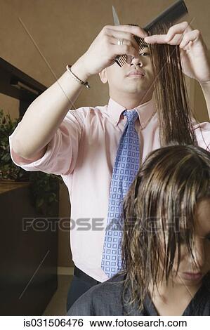 Stock Photograph - Asian male hairstylist cutting hair. Fotosearch