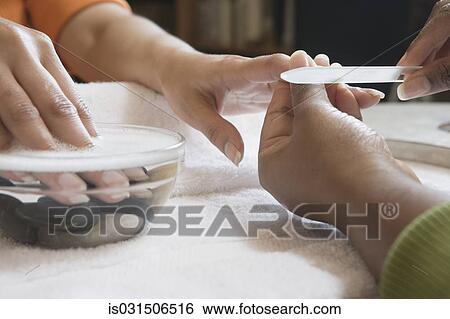 Stock Photograph - Close up of woman receiving manicure. Fotosearch
