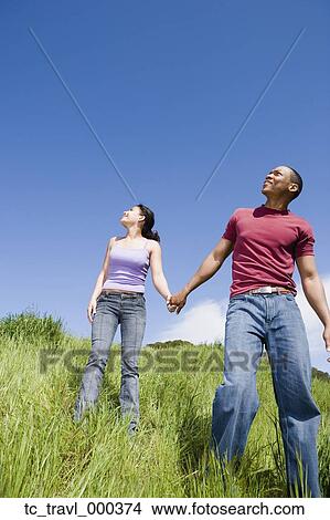 Picture - Couple holding hands and walking outdoors. Fotosearch