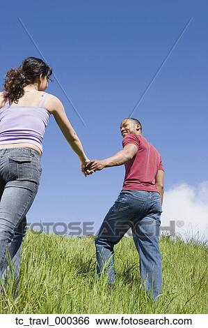 Stock Photograph - Couple holding hands and walking up hill. Fotosearch